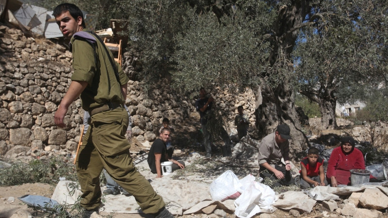 The Israel army guards Palestinian farmers from attacks by Jewish settlers from the nearby Israeli settlement of Tal Rumeda near the West Bank city of Hebron