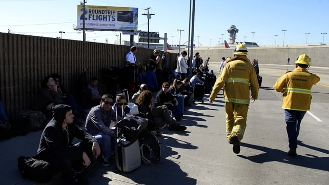 People sit outside awaiting clearance to re-enter the airport