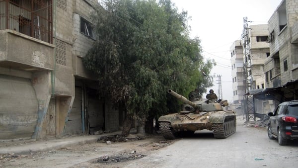 A Syrian army tank moves through the streets of Sbeineh