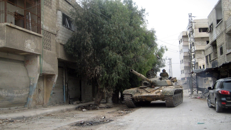 A Syrian army tank moves through the streets of Sbeineh