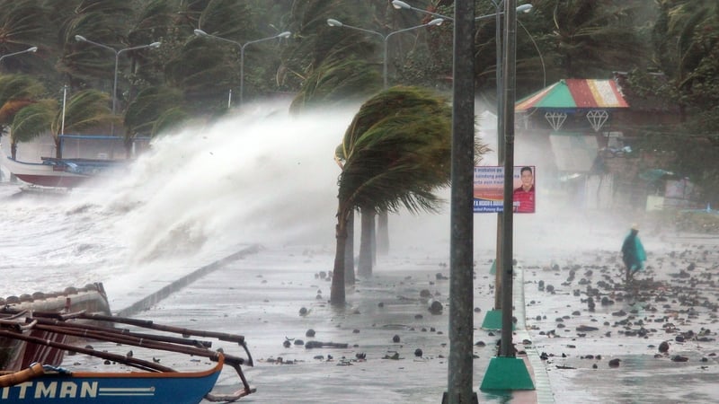 A resident walks past high waves pounding the sea wall in strong winds in the city of Legaspi, south of Manila