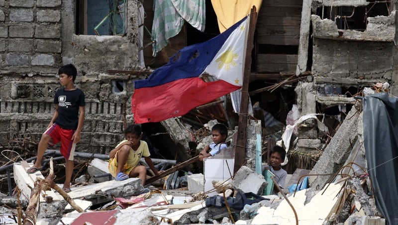 Filipino children stand in the rubble of houses in the devastated town of Hernani, Eastern Samar province