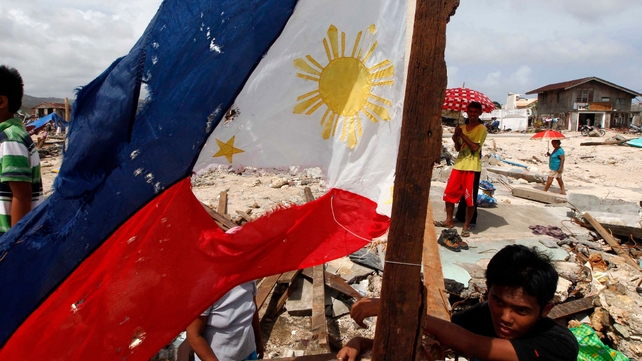 Children are seen next to a worn out Philippines flag in Hernani