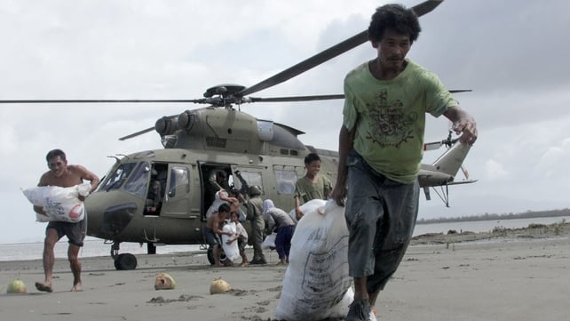 Survivors at the coastal village of Capiz carry sacks containing relief goods delivered via helicopter by the Armed Forces of the Philippines