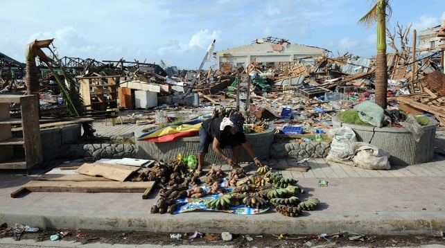 A fruit seller sets up a stall beside a ruined fruit market in the Philippines