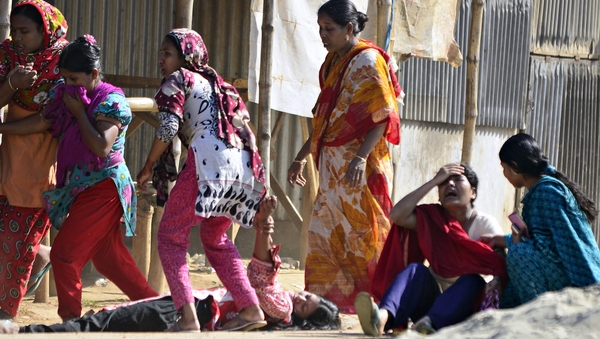 Bangladeshi garment workers on the ground as others react after riot police fired tear gas shells during clashes in Ashulia