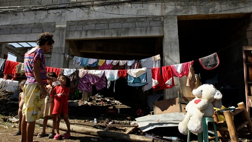 A Filipino woman shares a bottle of water with her grandchildren