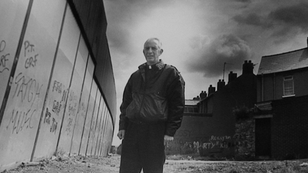 Father Alec Reid by one of Belfast's peace walls
