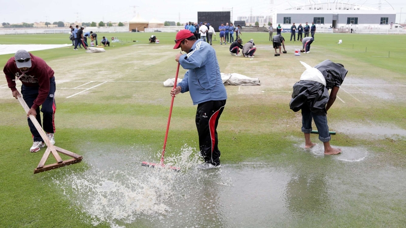 Ground staff move water off the playing surface