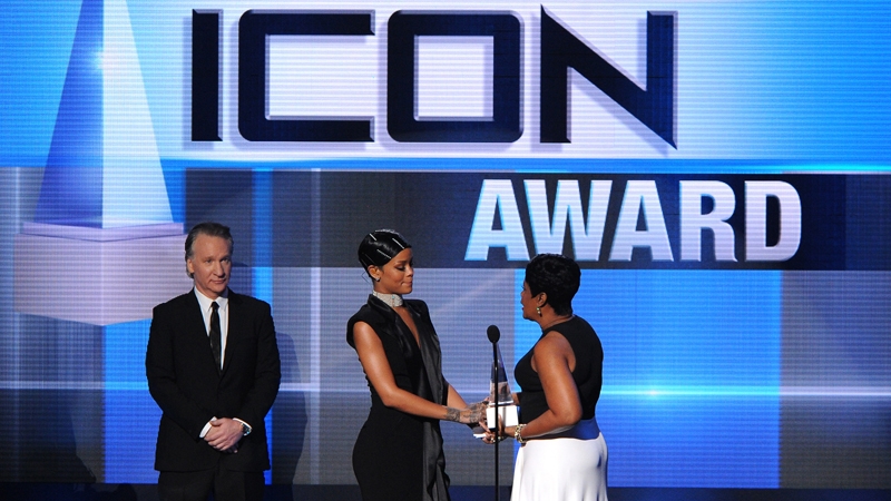 Rihanna accepting the award from her mum Monica as Bill Maher looks on