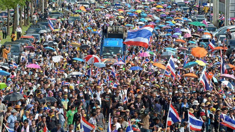 Anti-government protesters wave national flags as they parade during a demonstration in Bangkok