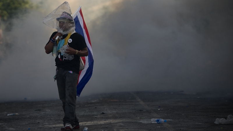 An anti-government protester uses a plastic bag on his head to avoid tear gas outside the Government house