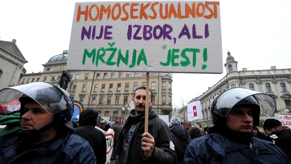 A protester holds a sign reading 'Homosexuality is not a choice, hate is a choice' next to riot policemen as Croatian gay rights activists protest in Zagreb