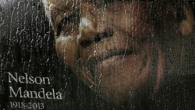 Rain falls on a poster of Nelson Mandela sitting in the window of a bus outside of Ellis Park