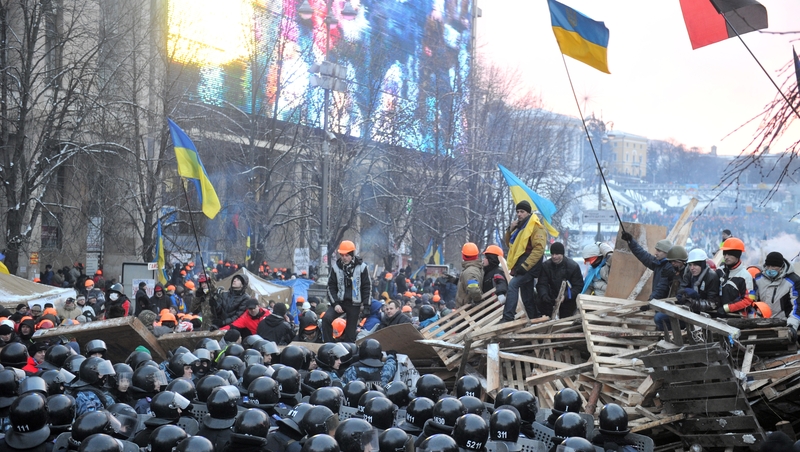 Riot policemen stand in front of a barricade held by protesters who defiantly refused to leave Independence Square