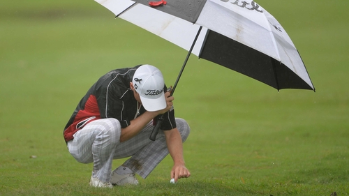 Michael Hoey attempts to remove his ball from the waterlogged turf in Durban