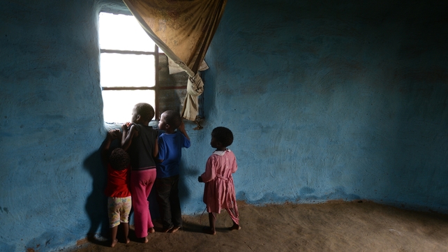 Local children watch crowds arrive outside their home at the burial site of Nelson Mandela