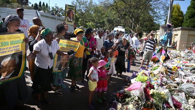 Crowds gather outside the home of Nelson Mandela in Johannesburg as he is laid to rest in his native village of Qunu