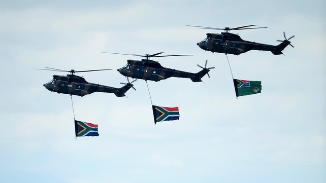 South African military helicopters fly over the burial site