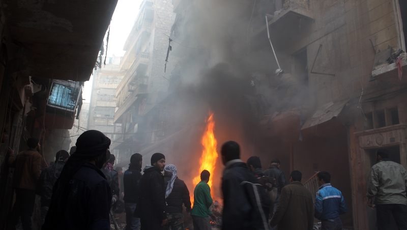 Syrians look at the aftermath of an airstrike on a rebel area of the war-torn northern city of Aleppo