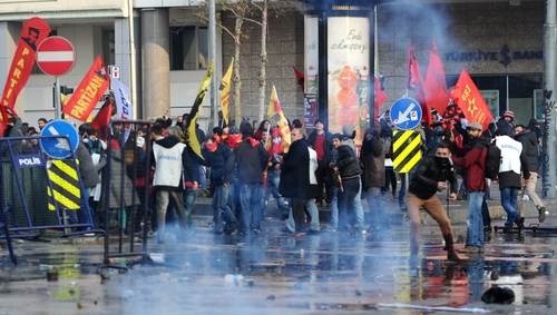 Protestors throw stones as riot police use tear gas and water cannon during a demonstration in Istanbul