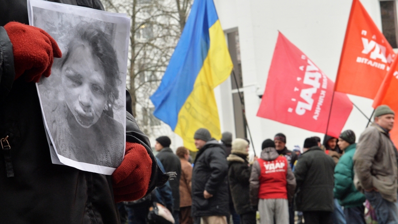 A protester holds a photo showing Tetyana Chornovil's injuries during a picket at the Internal Affairs Ministry in Kiev this morning