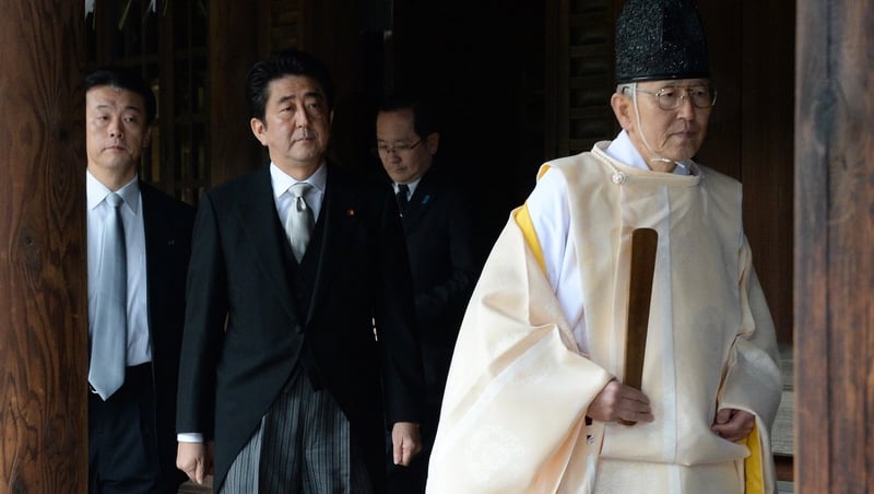 A Shinto priest leads Japanese Prime Minister Shinzo Abe (centre) as he visits the Yasukuni war shrine in Tokyo