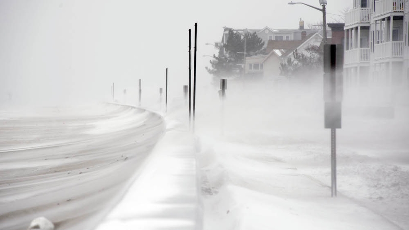 Winds whip snow from the beach across Winthrop Shore Drive in Winthrop, Massachusetts