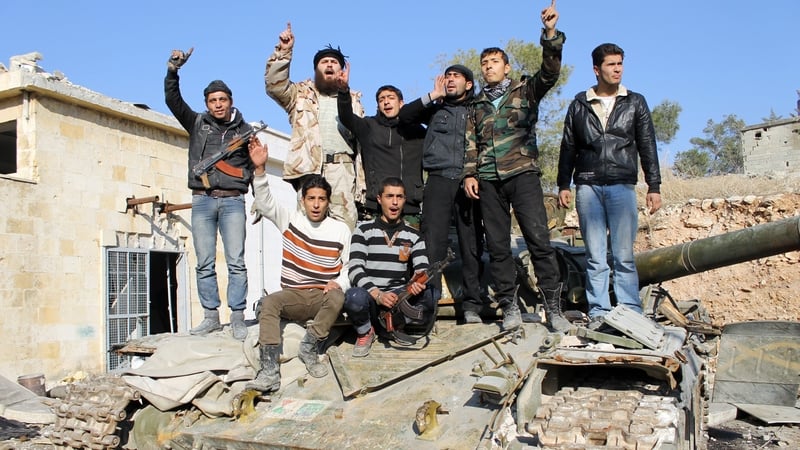 Rebel fighters stand on top of a tank confiscated from pro-regime fighters in the northern Syrian city of Aleppo on 21 December