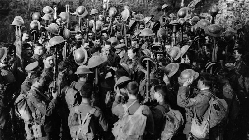 Men of the First Battalion of Irish Guards hold aloft their helmets as they hear the news of the Armistice