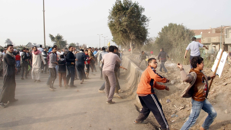 Egyptian Muslim Brotherhood supporters throw stones at voters outside a polling station
