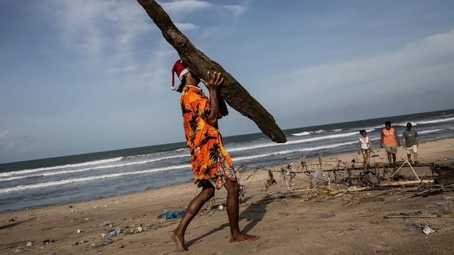 A volunteer carries a large piece of debris