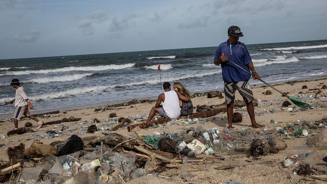 Tourists sit and watch as locals clear the beach
