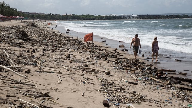 Tourists stroll along the trash-strewn beach