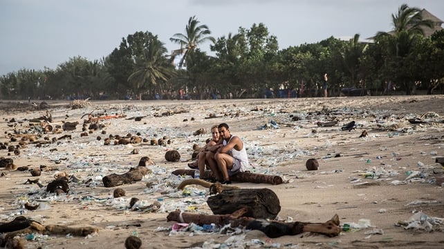Tourists sit among the waste