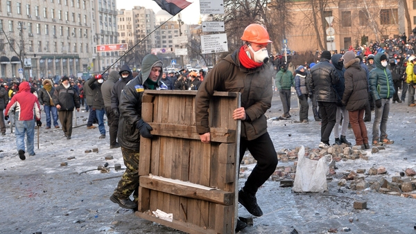 Protesters carry a wooden board to build barricades during clashes with the police in Kiev