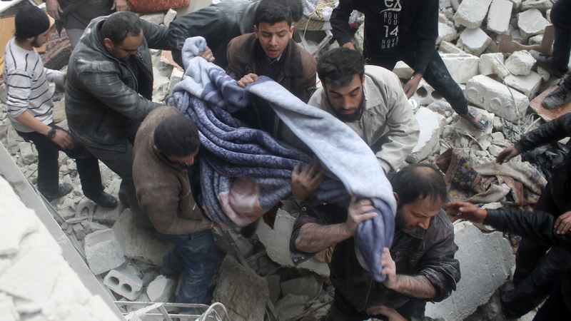 The body of a victim killed in an air raid on Aleppo is pulled from the rubble of a collapsed building