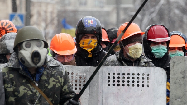 Protesters protect themselves from tear gas during an anti-government protest in Kiev