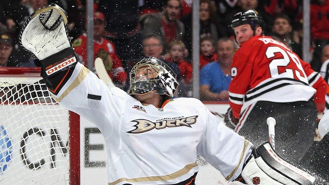 Jonas Hiller of the Anaheim Ducks tries to make a save on a goal shot by Bryan Bickell of the Chicago Blackhawks in Chicago