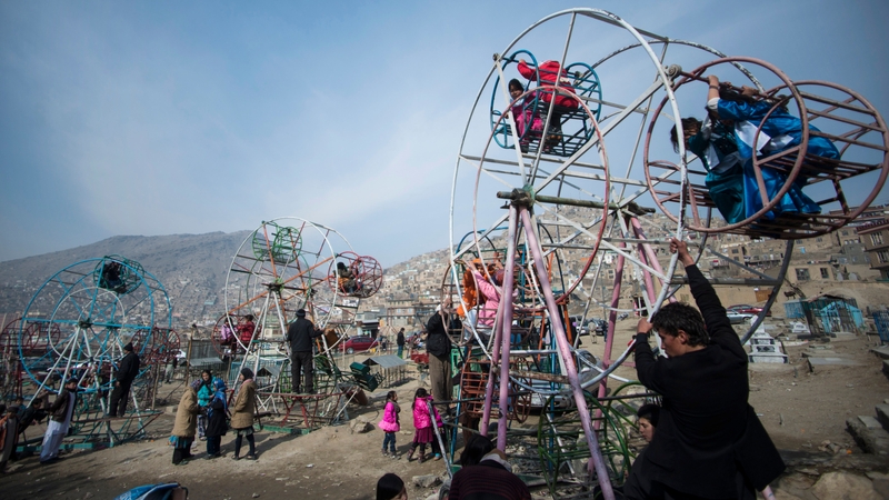 Afghan children ride on ferris wheels near a cemetery in Kabul