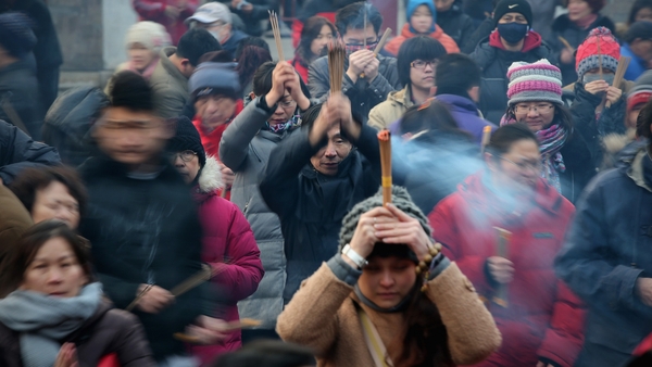 Chinese people pray for good fortune as they hold burning incense