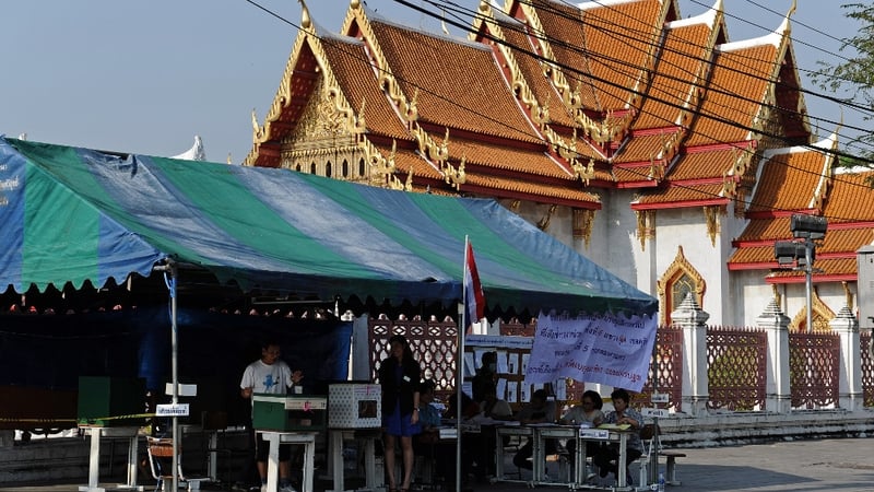 A Thai voter (L) cast his vote at an outdoor polling station in downtown Bangkok