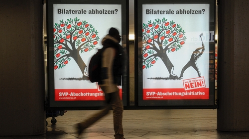 A man passes a political banner against immigration quotas in advance of today's referendum