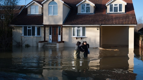 People wade through deep floodwater outside a home in Wraysbury, west of London