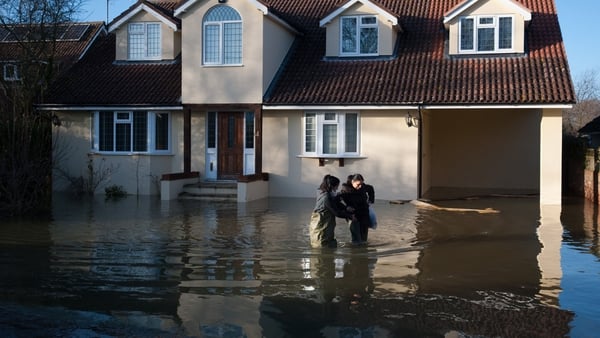 People wade through deep floodwater outside a home in Wraysbury, west of London