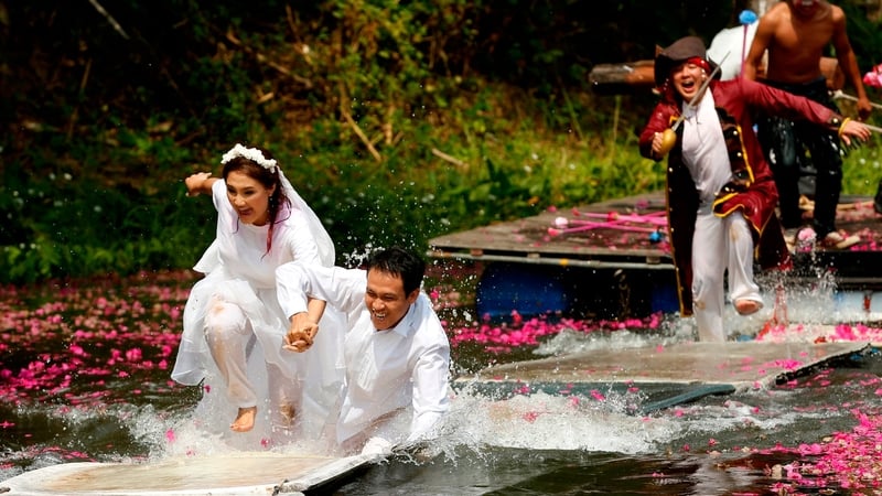 Newly-married Thai couple Wichan Wina and Walailuk Rungros join hands as they run away from 'pirates' during their adventure wedding challenge celebrating Valentine's Day in Prachin Buri province, Thailand (Pic: EPA)