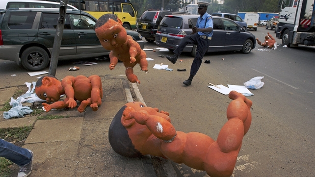 A Kenyan policeman kicks a foam sculpture of a baby left by a protester, after demonstrators were dispersed by tear gas during an anti-corruption protest in Nairobi