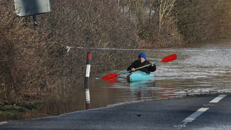 A man paddles his canoe down the flooded main A361 road as it enters the village of East Lyng