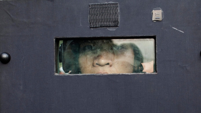 A Thai police officer peers through the eye slit of his riot shield as police storm an anti-government protest camp near Government House in Bangkok