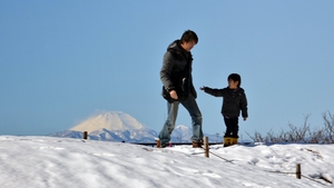 A boy and his father walk on a snow covered field in Tokyo while snow covered Mount Fuji is seen in the background. Two people were killed when a fresh snow storm hit Japan, disrupting rail and road travel, and grounding more than 100 flights.